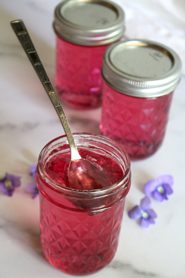 Homemade violet jelly is thick enough to hold a spoon, but smooth and spreadable on toast