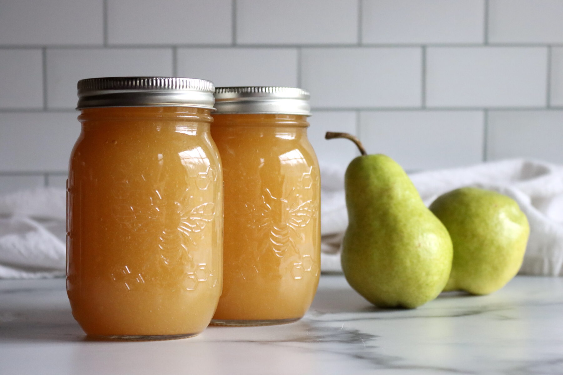 Pear Honey in jars against a white background.