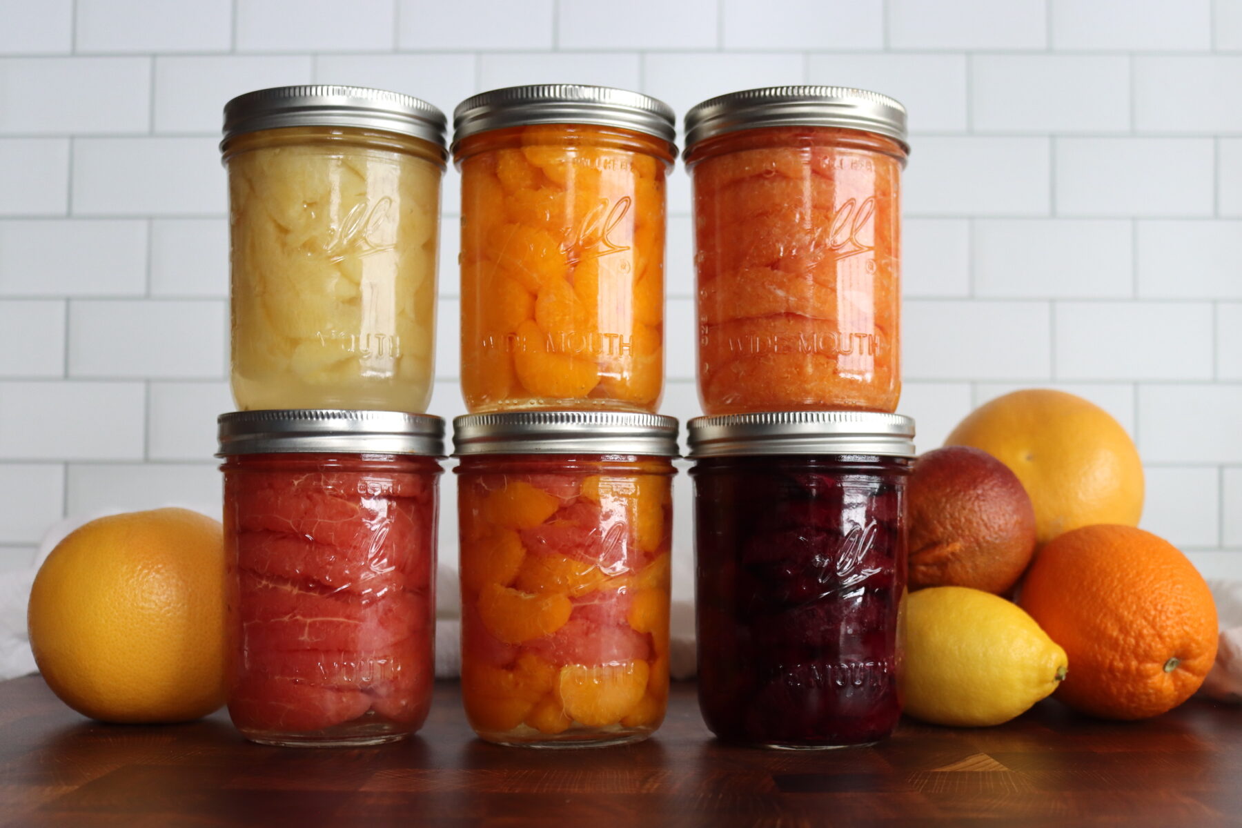 Canning Citrus Segments. First row, Candied lemon segments, orange, cara cara orange, blood orange, orange/grapefruit mix, and grapefruit.
