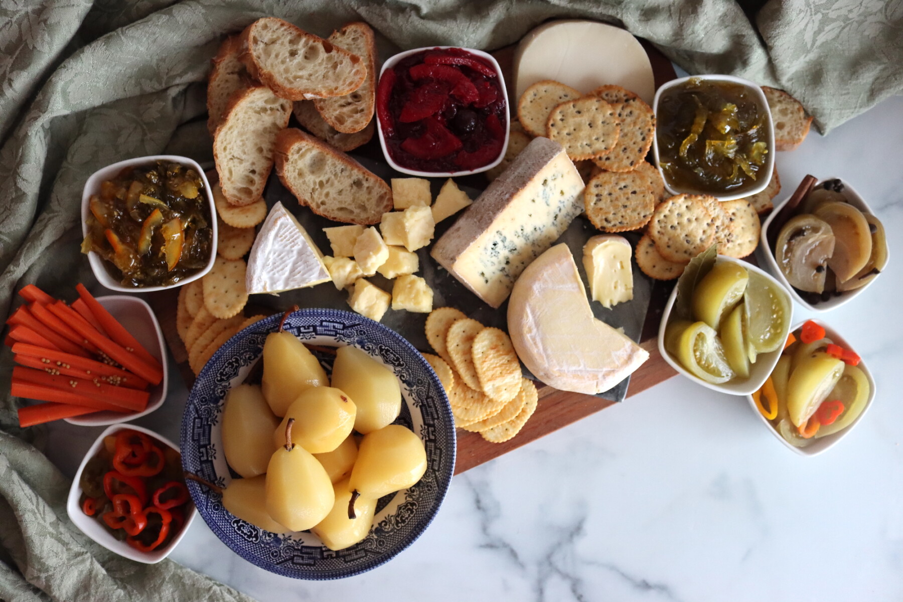 Holiday charcuterie platter with cheese, pickled pears, pickled green tomatoes, cranberry orange marmalade, green tomato preserves, pickled carrots, pickled peppers and green tomato marmalade.