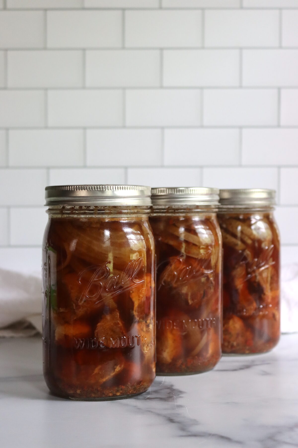 Quart jars of canned pork on a white countertop.