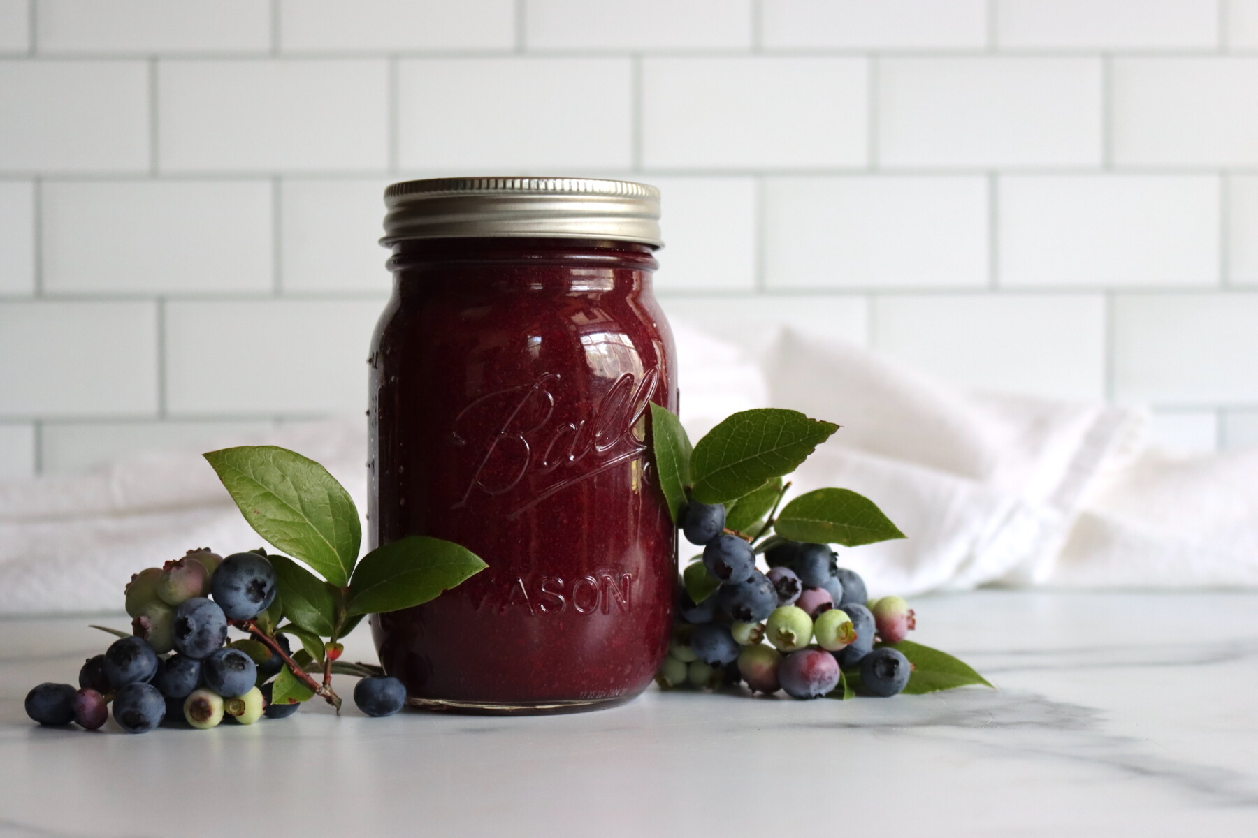 Blueberry applesauce in canning jars with fresh blueberries