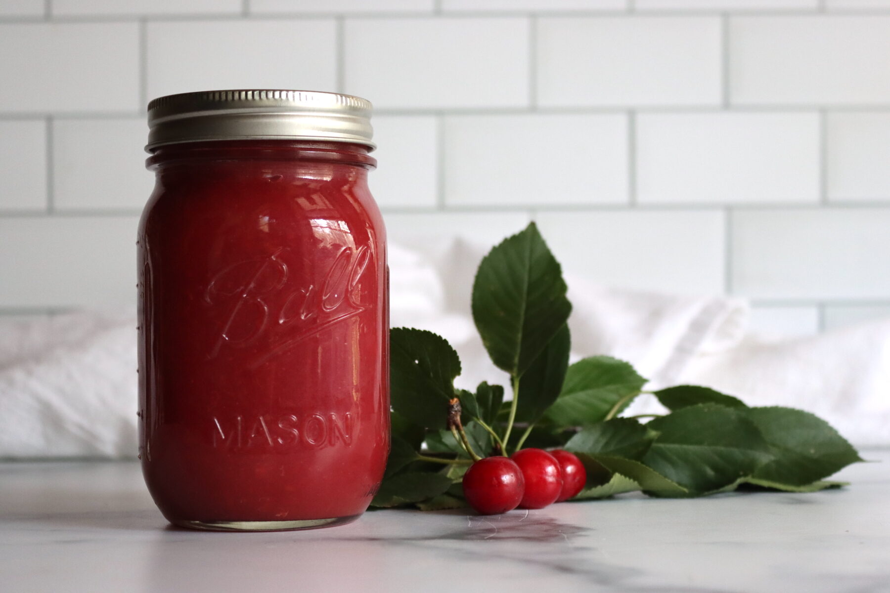 Cherry applesauce in canning jars with fresh cherries