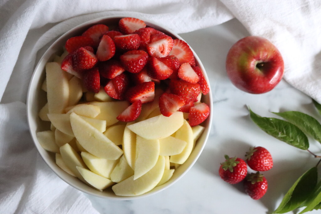 Ingredients in a bowl prepared for making strawberry applesauce.