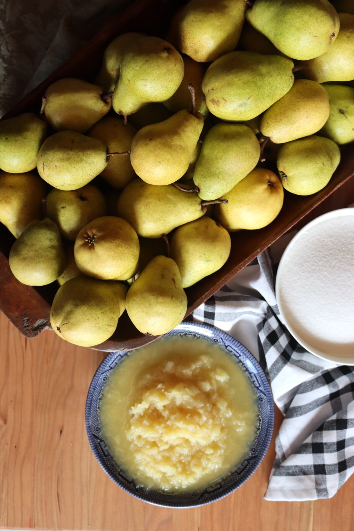 Overhead view of fresh pears, sugar, and crushed pineapple on a wooden table