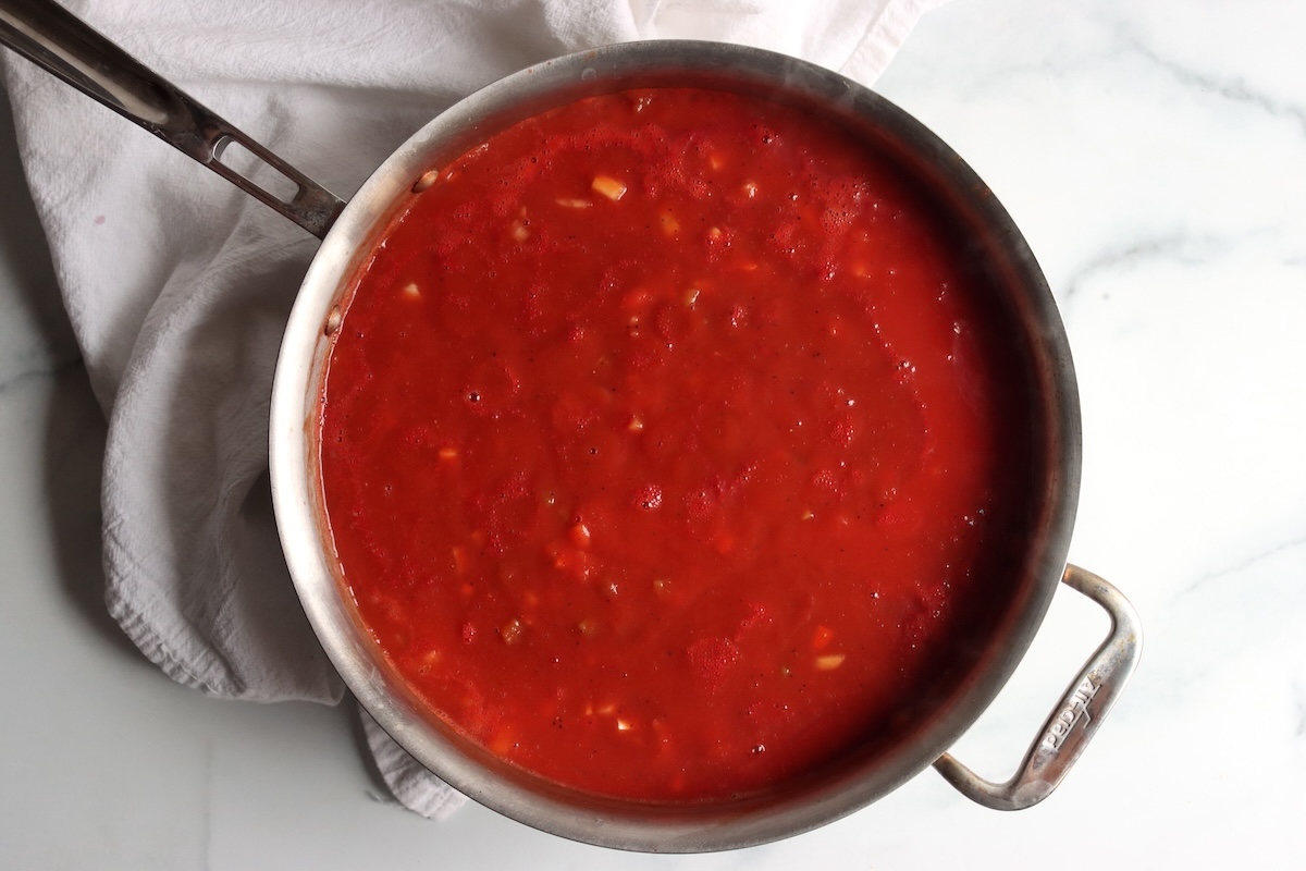 Italian-style tomato sauce cooking down in a stainless steel pan