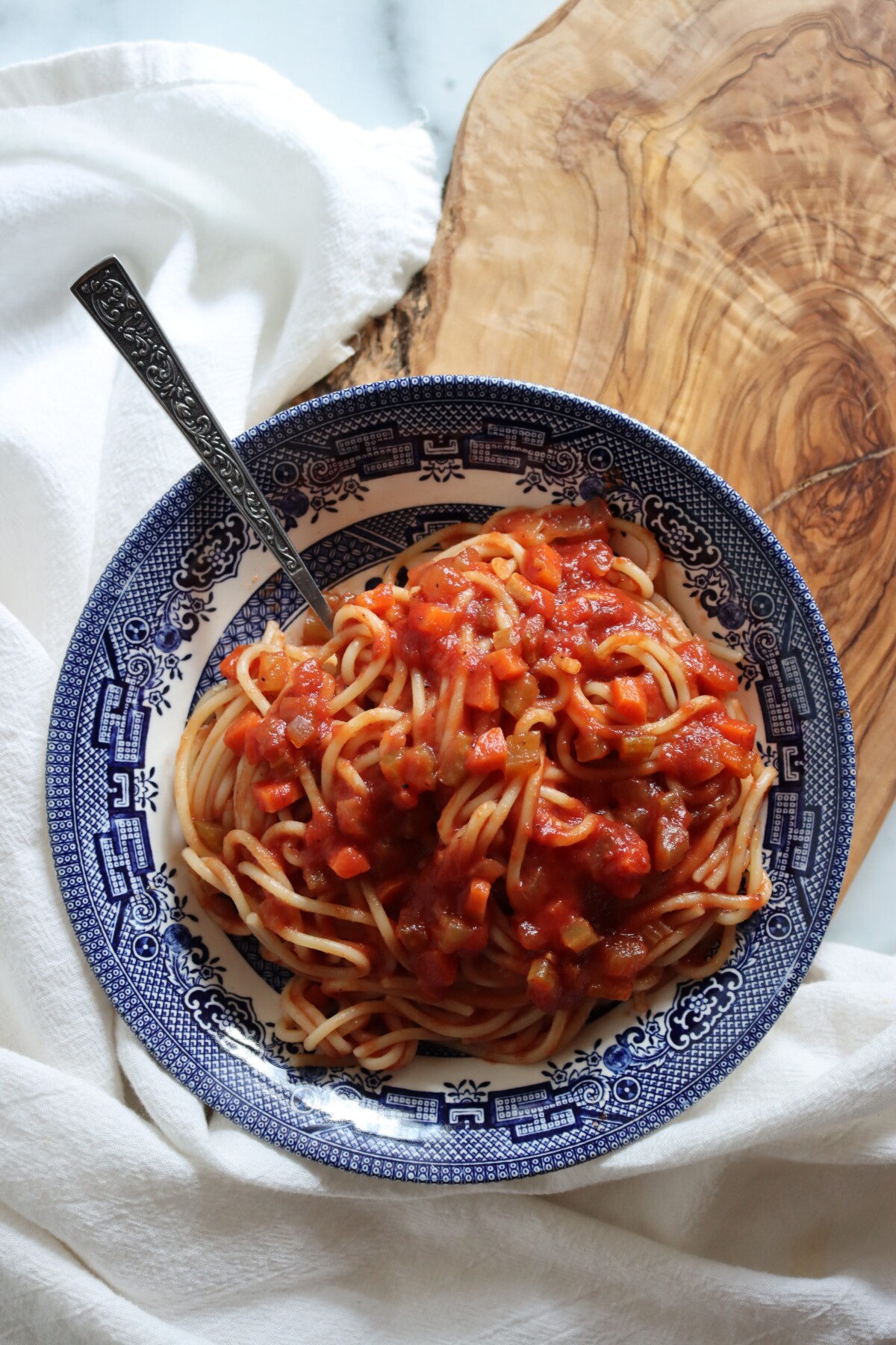 Spaghetti topped with Italian-style tomato sauce in a blue and white bowl with a fork