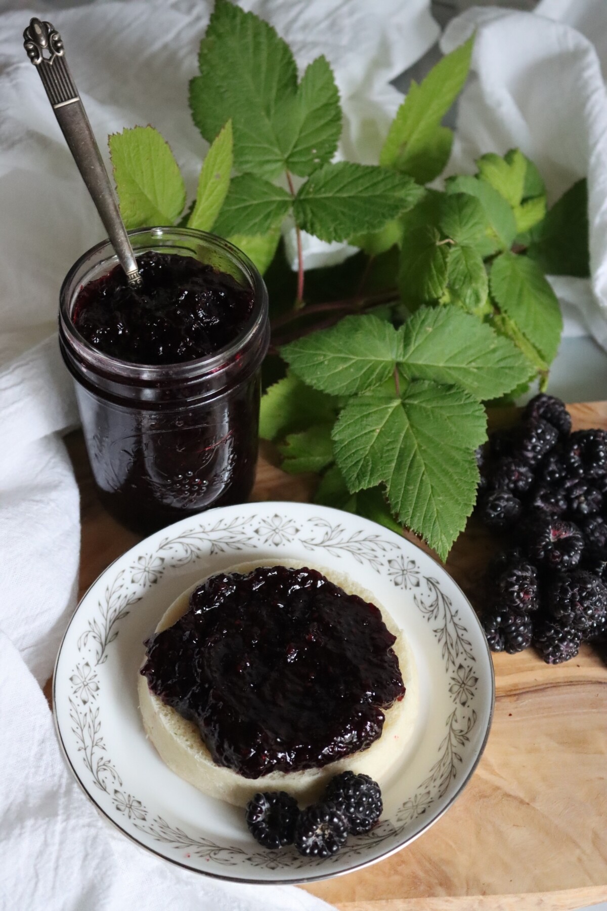Open jar of black raspberry jam with jam spread on an English muffin