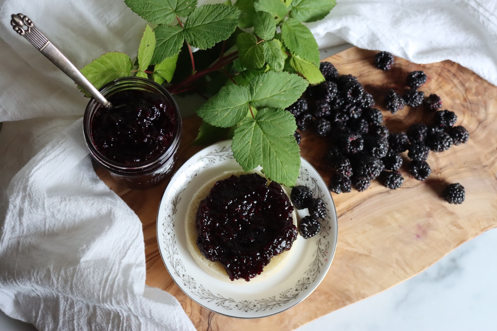 Homemade black raspberry jam on a plate with fresh blackcaps