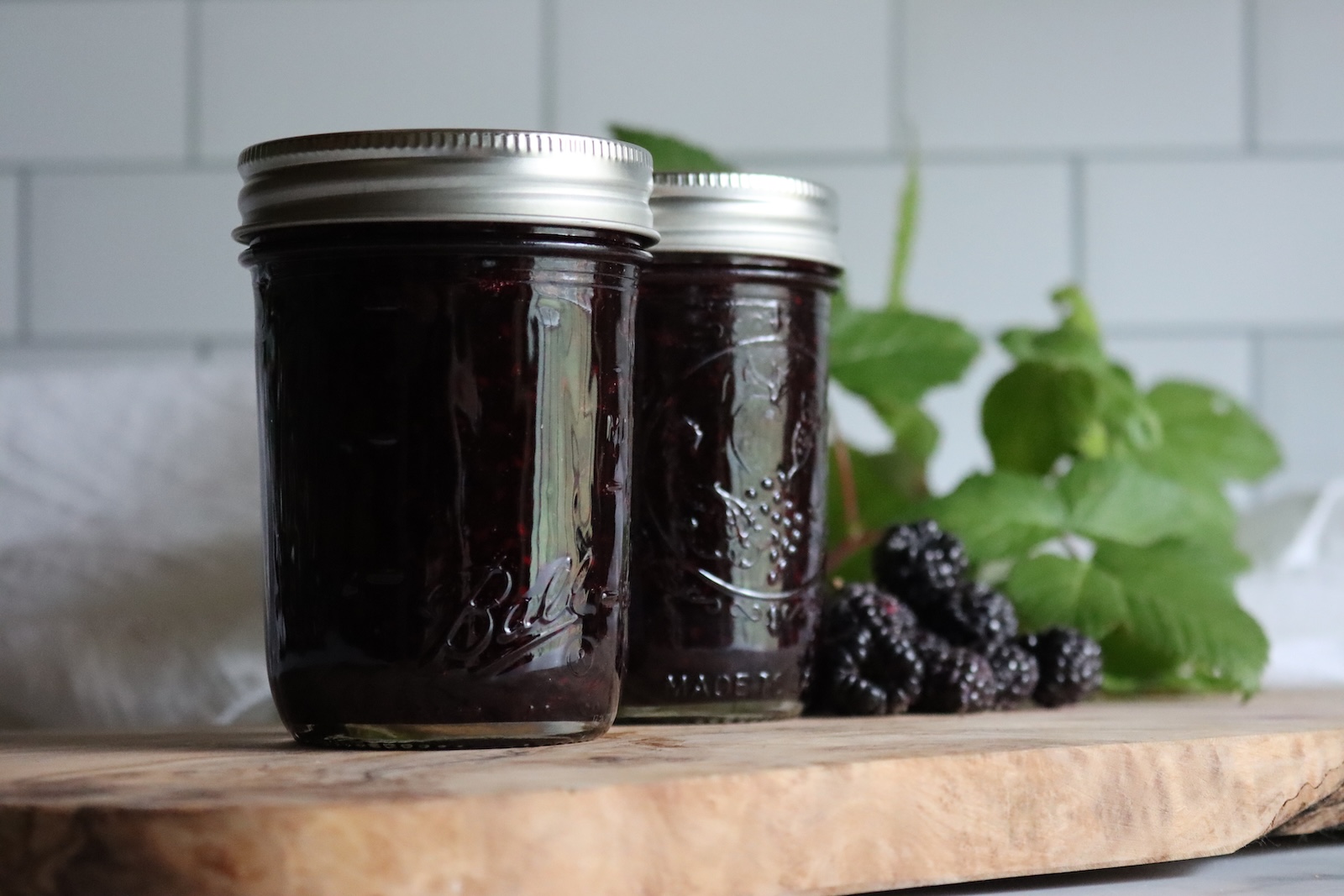 Two jars of black raspberry jam with fresh black raspberries