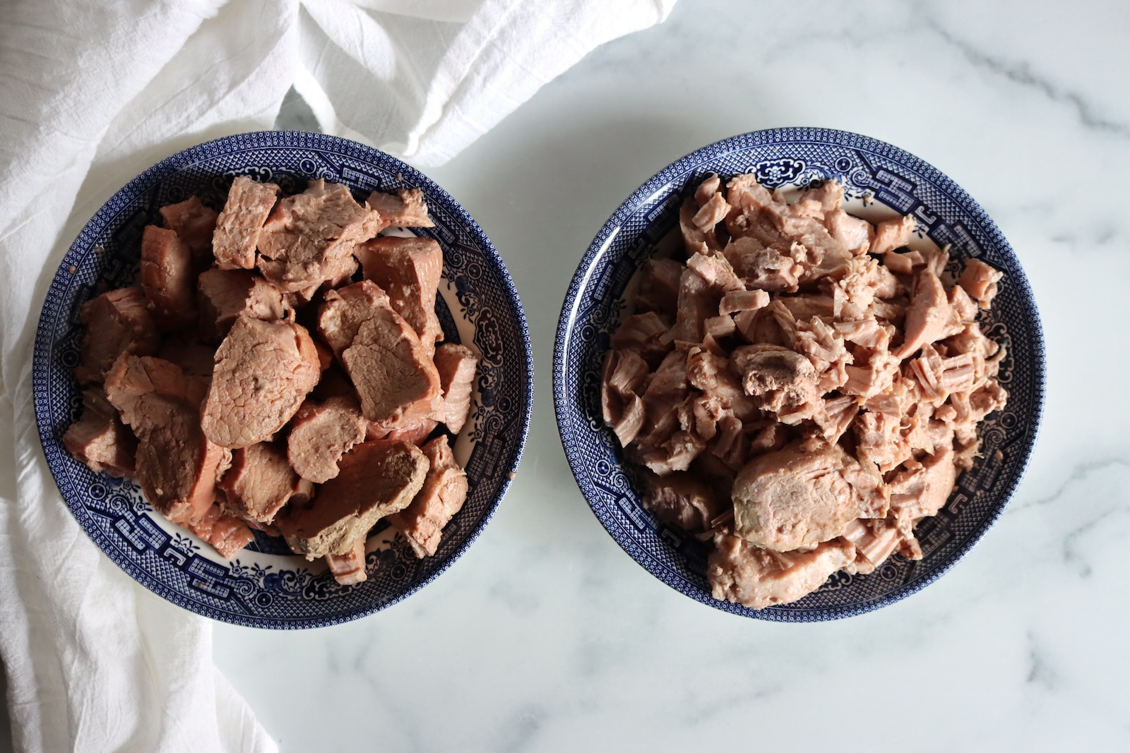 Bowls of hot pack and raw pack canned pork tenderloin side by side, slices on the left and shreds on the right