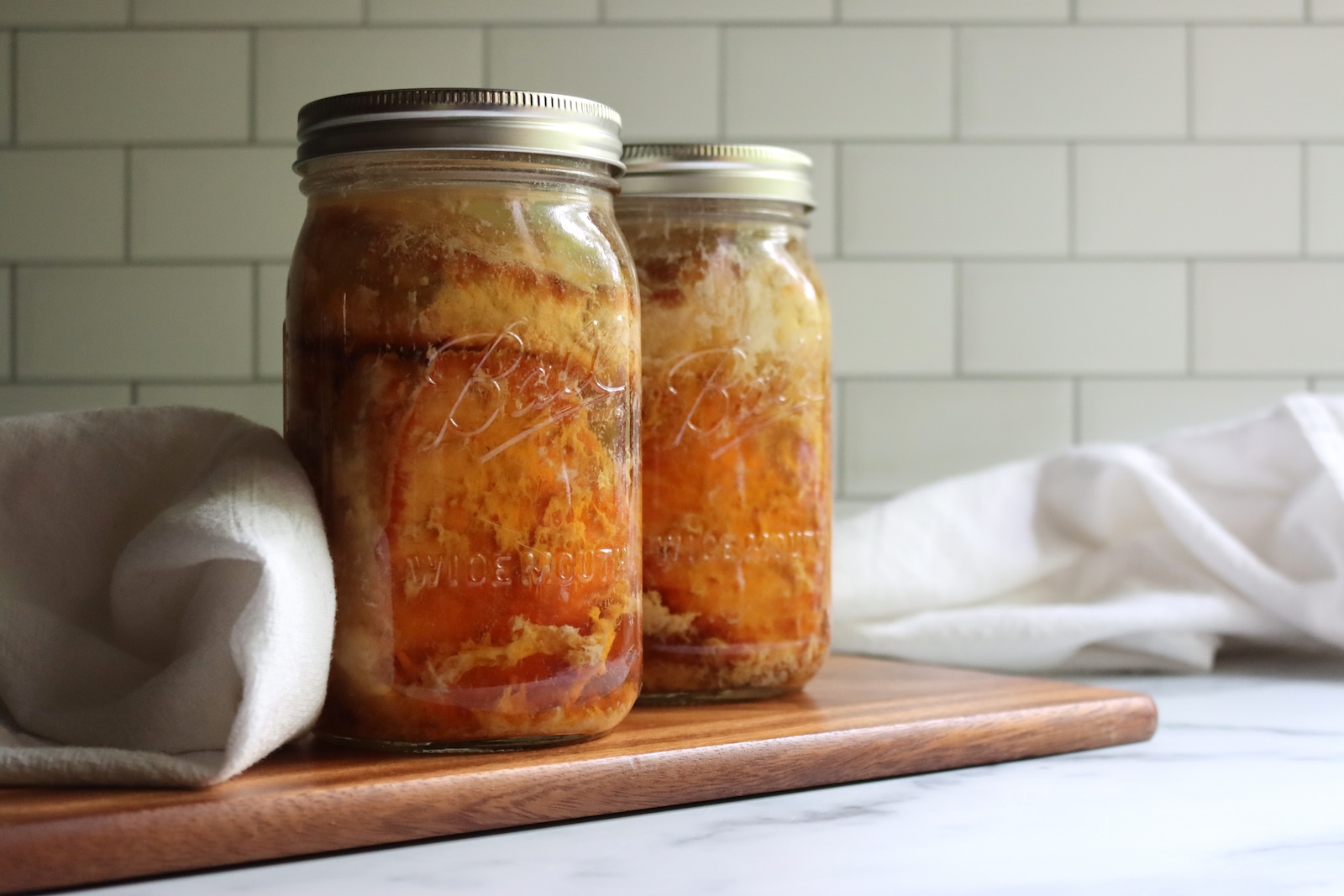 Quart and pint jars of home-canned pork chops on a wooden cutting board