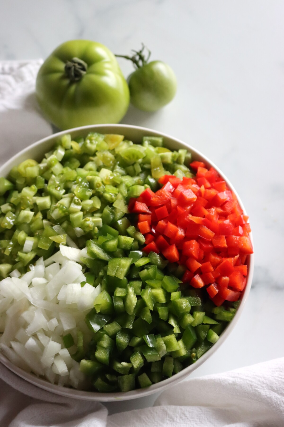 Bowl of chopped green tomatoes, bell peppers, and onion for green tomato hot dog relish