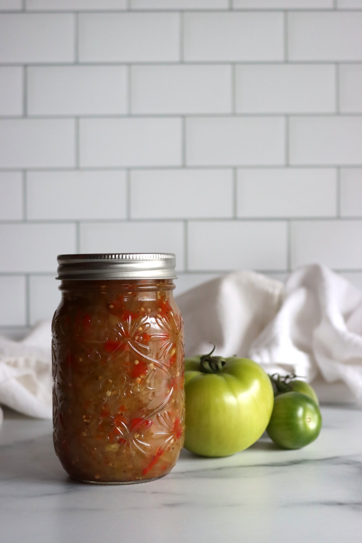 Sealed pint jar of green tomato relish on a marble counter