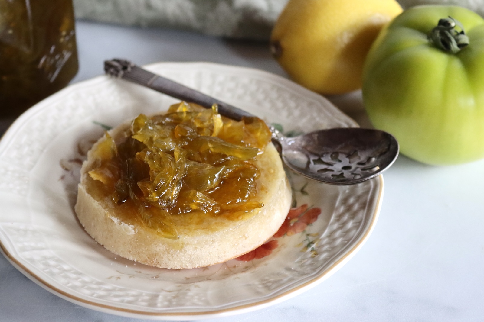Green tomato preserves spread on an English muffin with a slotted spoon