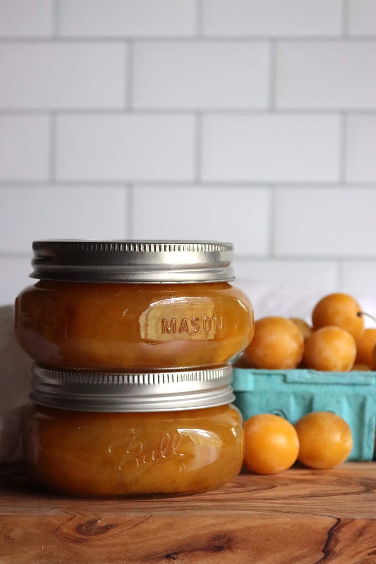 Two half-pint jars of mirabelle plum jam with fresh mirabelles