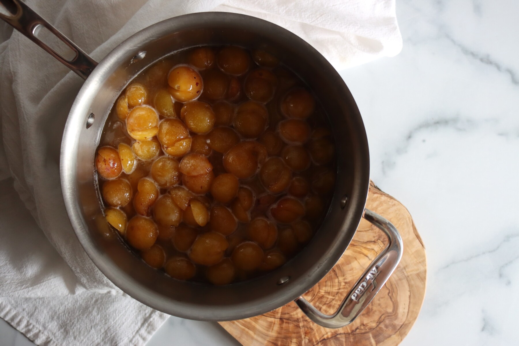 Halved mirabelle plums in a stainless steel pot, ready to cook into jam