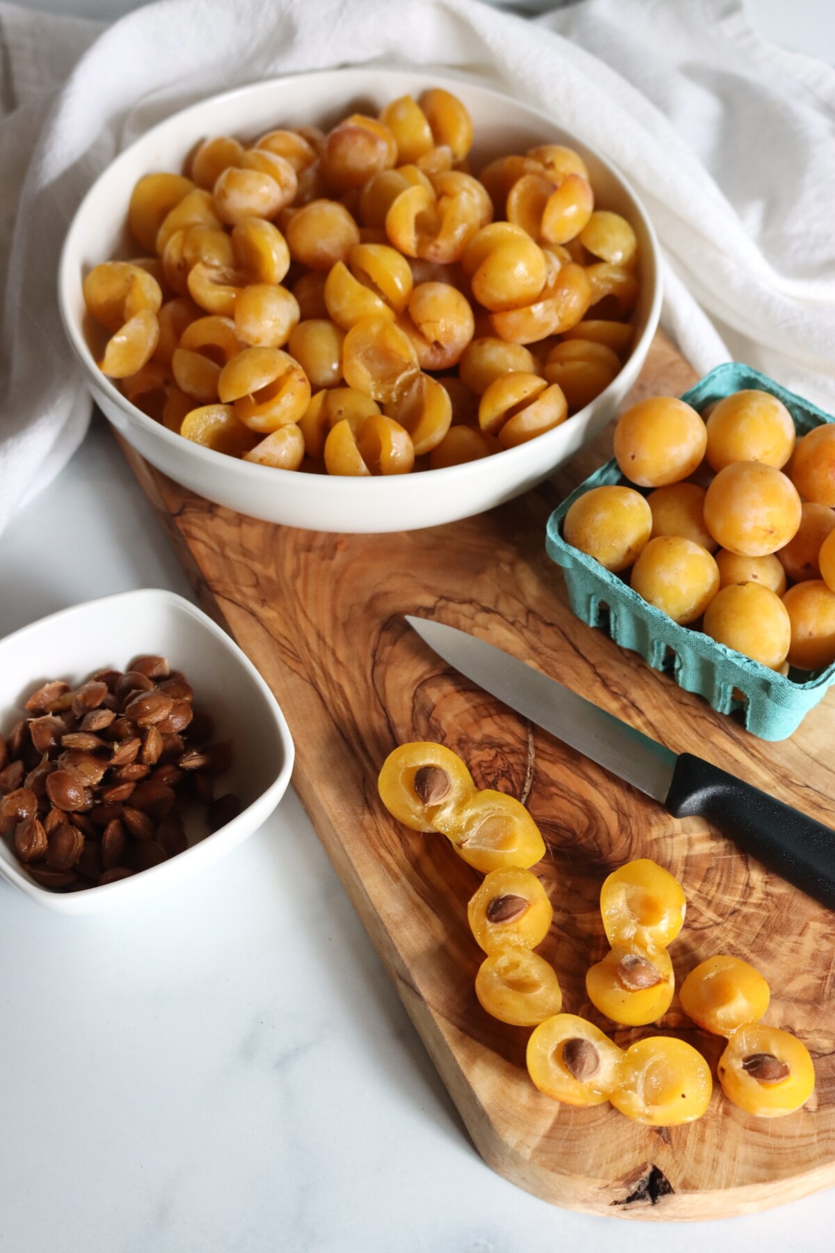 A bowl of halved mirabelle plums with the pits removed